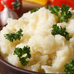 Delicious mashed potatoes with parsley in a bowl macro on a table against the background of vegetables. horizontal. rustic style