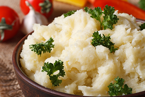 Delicious mashed potatoes with parsley in a bowl macro on a table against the background of vegetables. horizontal. rustic style