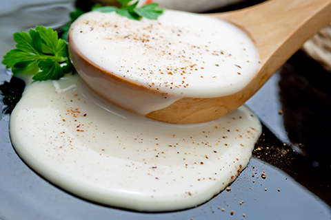 Closeup of bechamel sauce (white sauce) in a wooden spoon
