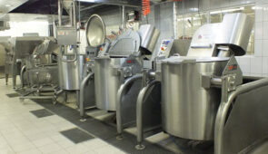 Industrial steam jacketed kettles being used in a food factory.
