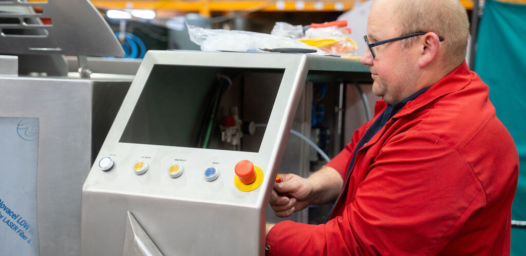 Technician operating industrial cooking equipment control panel to prevent downtime in food processing production.
