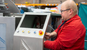 Technician operating industrial cooking equipment control panel to prevent downtime in food processing production.