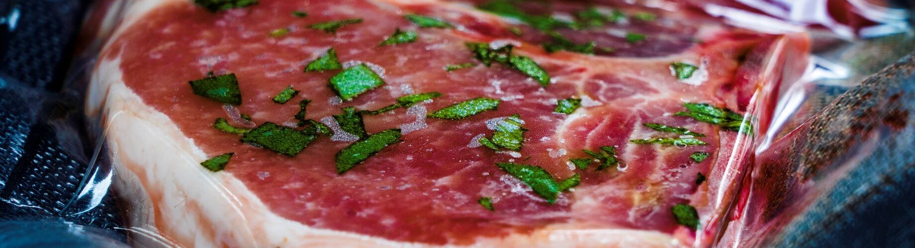 meat sealed in vacuum bag cooked using industrial sous vide machine in temperature-controlled water bath.