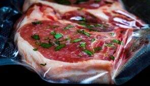 meat sealed in vacuum bag cooked using industrial sous vide machine in temperature-controlled water bath.